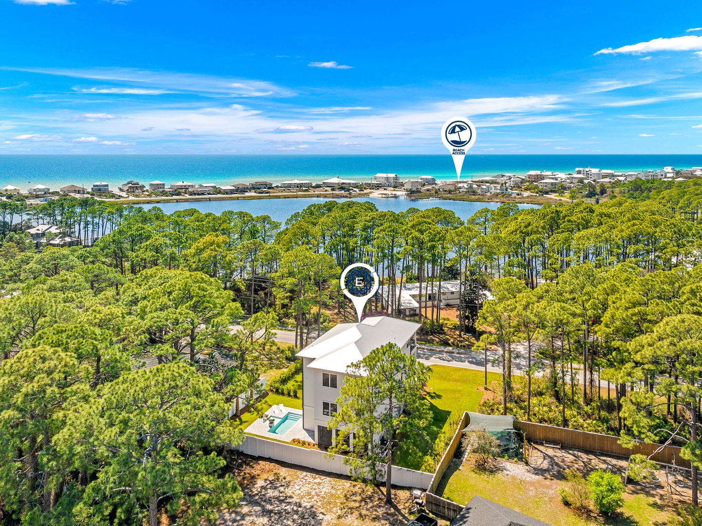 Coastal vacation rental nestled among towering pines, positioned between pristine beach and tranquil lake waters.
