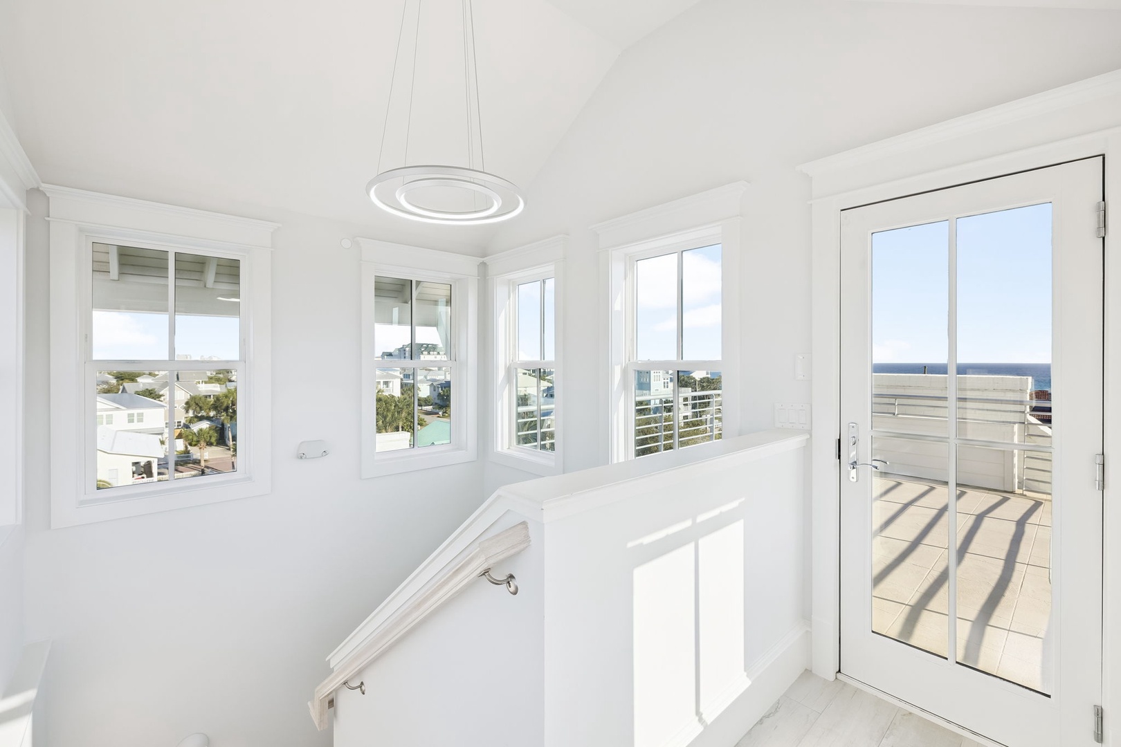 Step into your bright stairway landing where panoramic windows frame stunning sea views and your private terrace awaits.