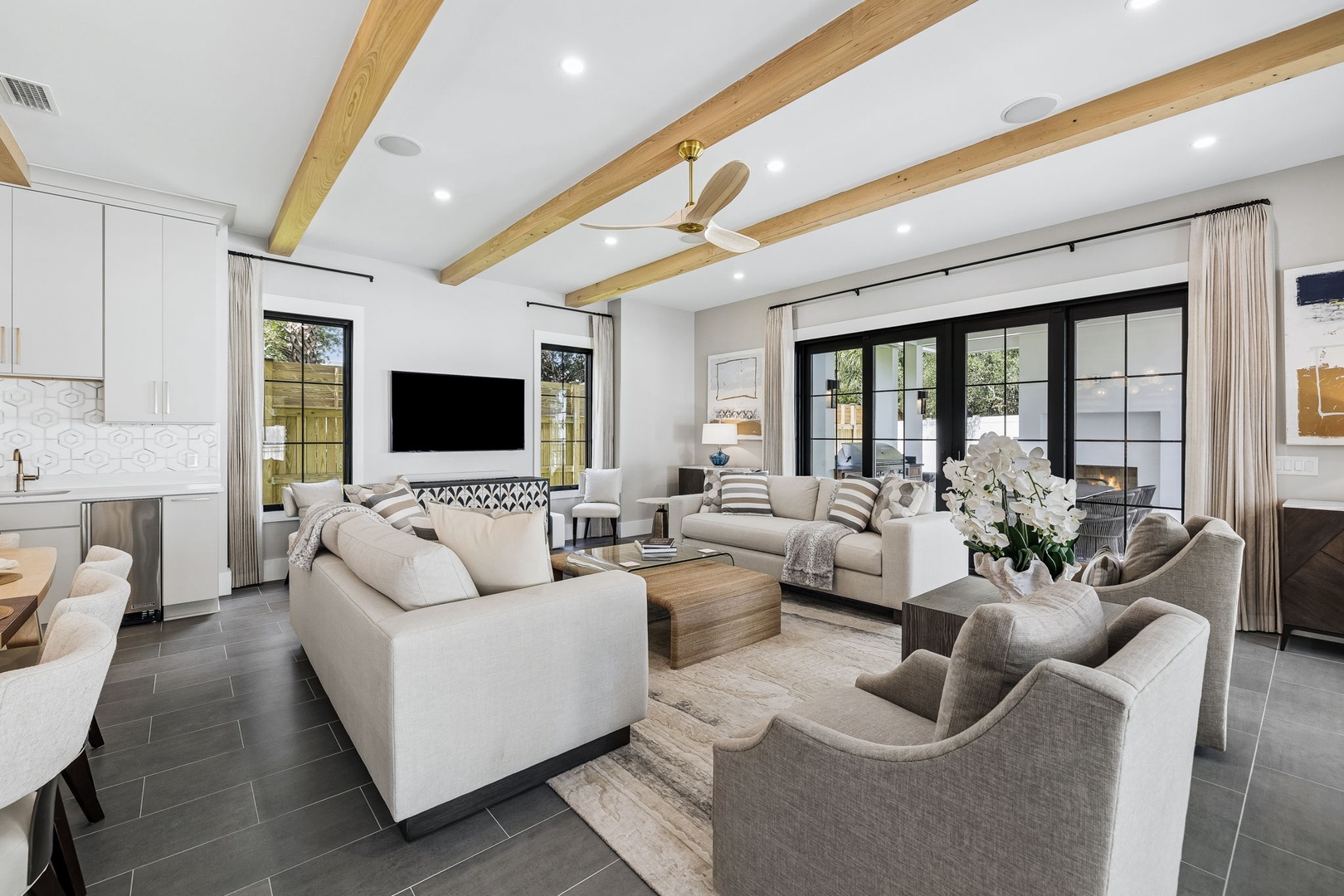 Settle into this bright, open living space where natural light pours in and vaulted wood beams add warmth overhead. Sink into plush sofas, gather with friends, or simply unwind beneath the gentle breeze of the ceiling fan as you enjoy your vacation.