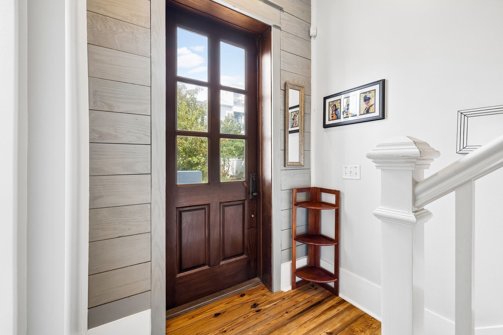 A charming entryway with shiplap walls and gleaming hardwood floors welcomes you into your vacation retreat, complete with curated artwork and thoughtful design touches.
