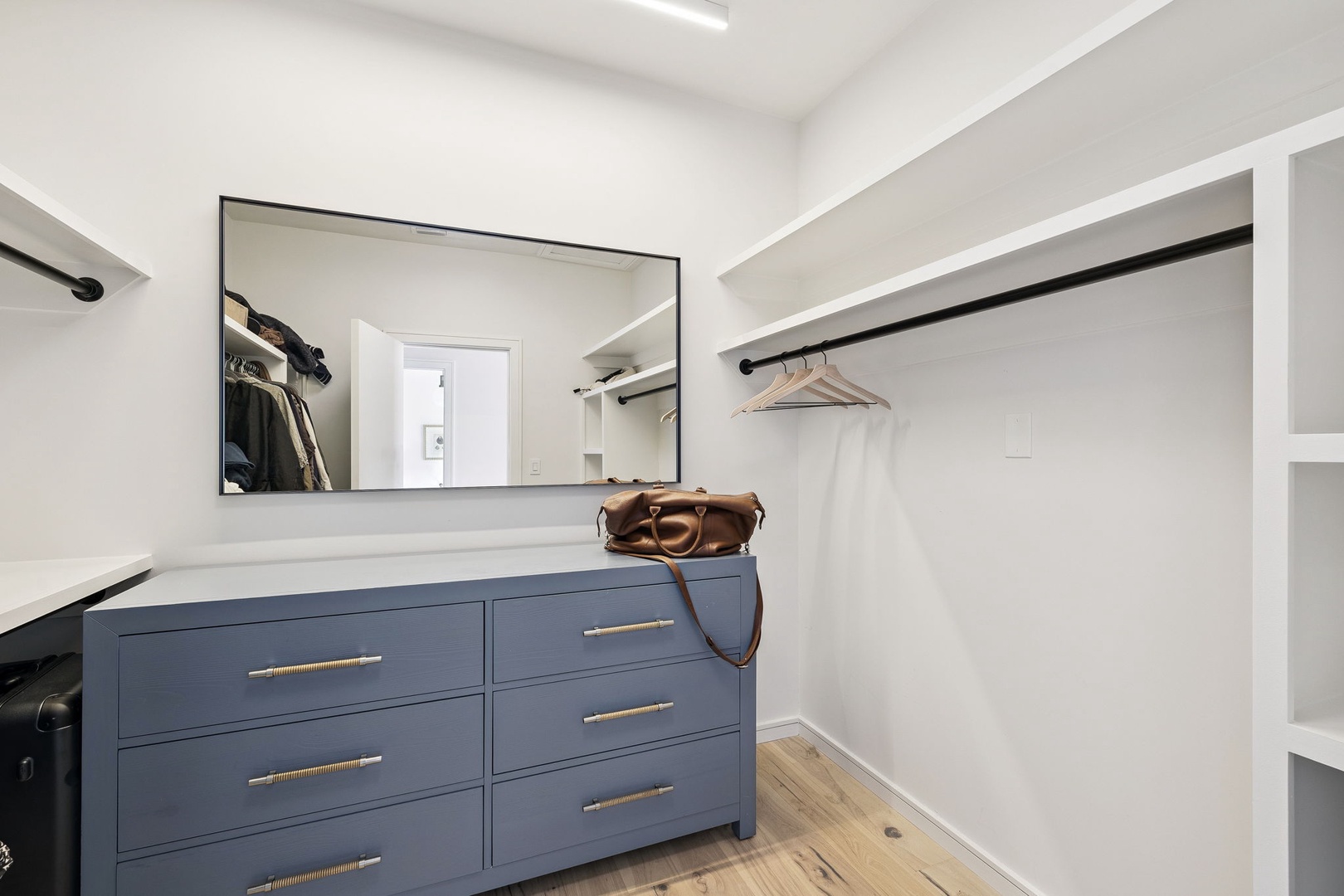 Your walk-in closet offers generous hanging space and stylish blue drawers, creating the perfect organized retreat for your wardrobe.