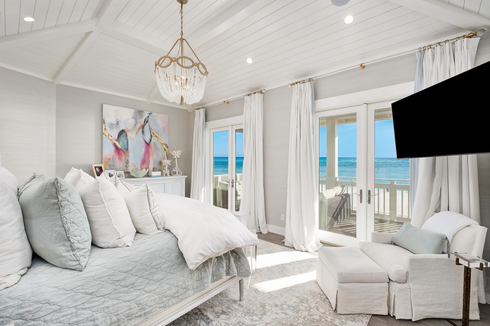 Picture yourself waking to brilliant ocean views framed by elegant white curtains, sunlight streaming across plush bedding and a cozy seating nook perfect for morning coffee or evening relaxation.