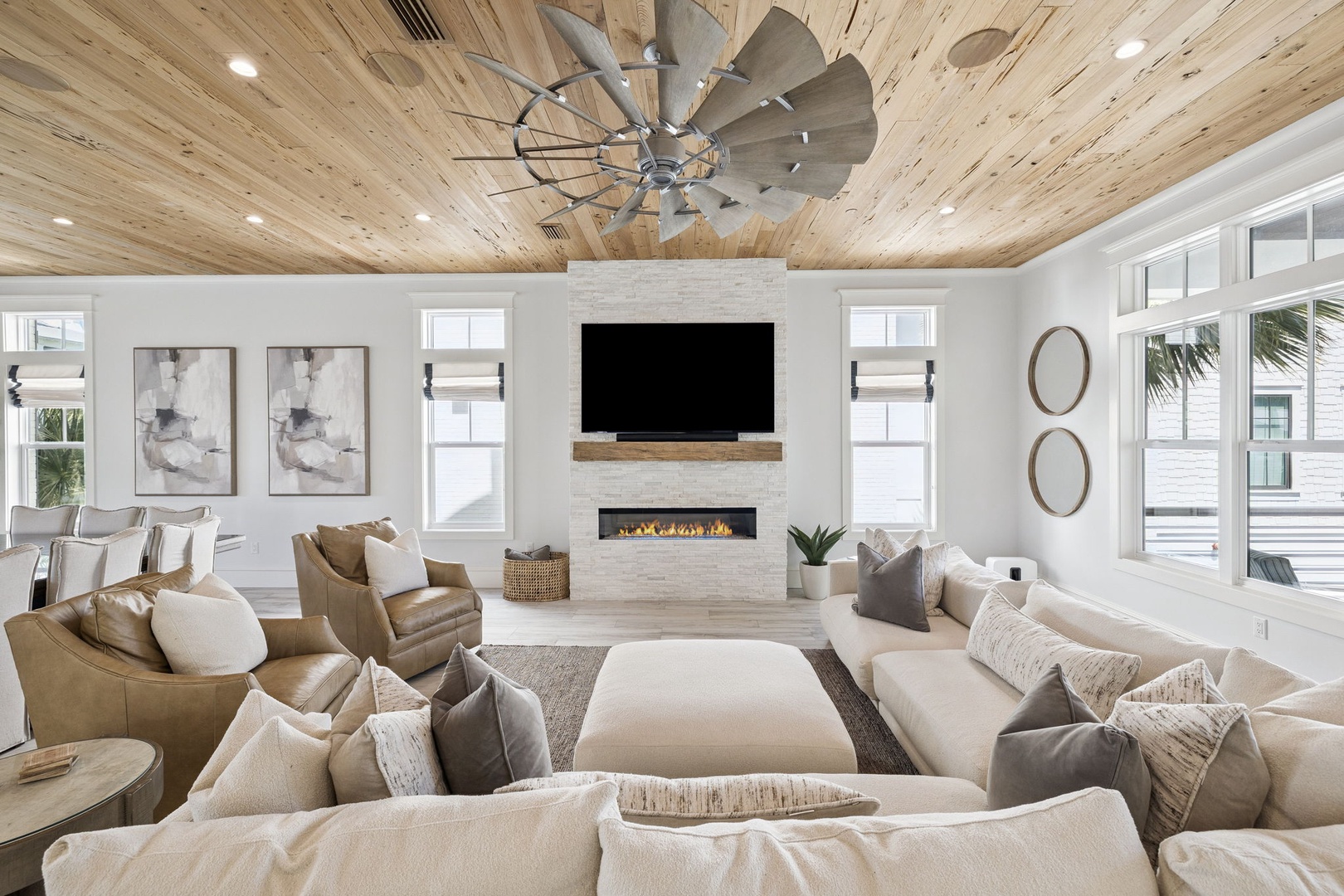Sink into plush seating beneath stunning wood ceilings, where modern fireplace warmth meets coastal charm for your perfect retreat.