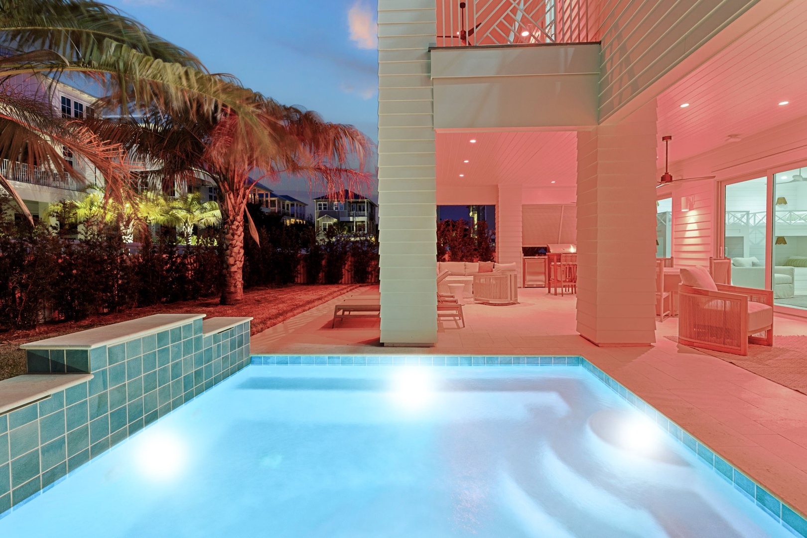 Your private pool oasis awaits under dramatic coral lighting, with tropical palms swaying nearby creating your own resort-style paradise.