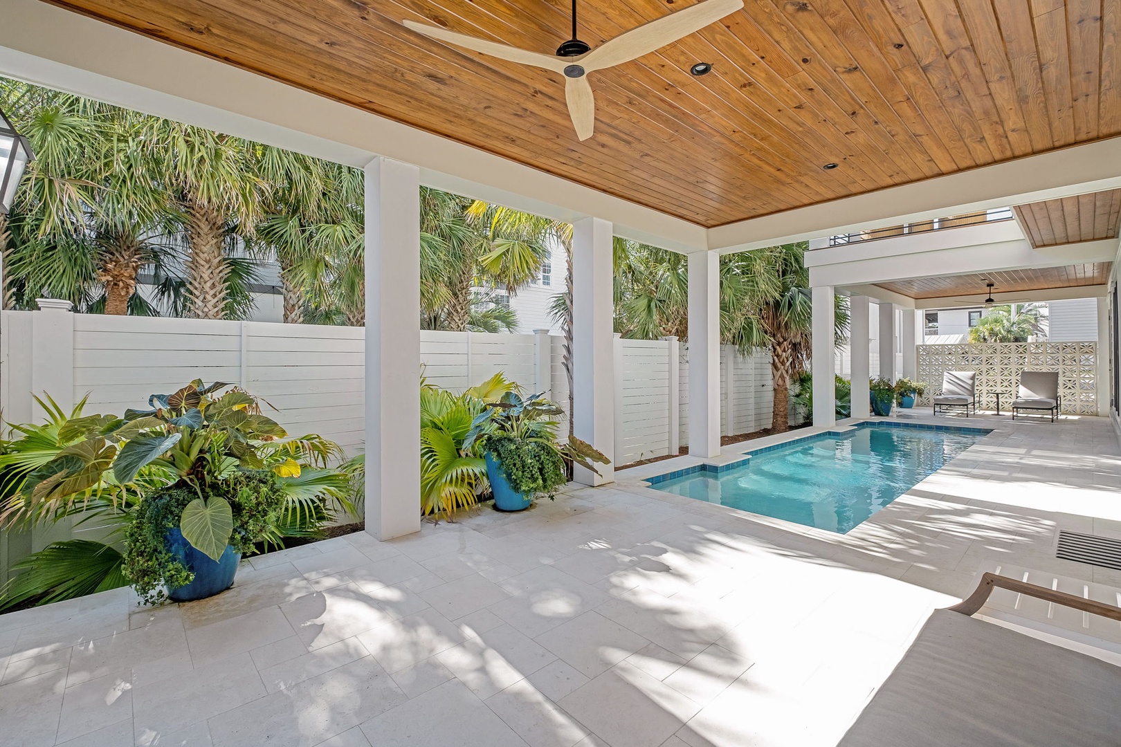 Your private pool oasis awaits with tropical landscaping and covered poolside lounging under soaring wood ceilings.