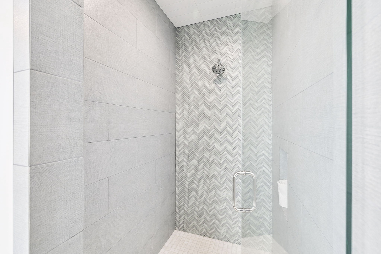 Step into your elegant glass-enclosed shower featuring beautiful herringbone accent tiles and modern fixtures for a refreshing start to your day.