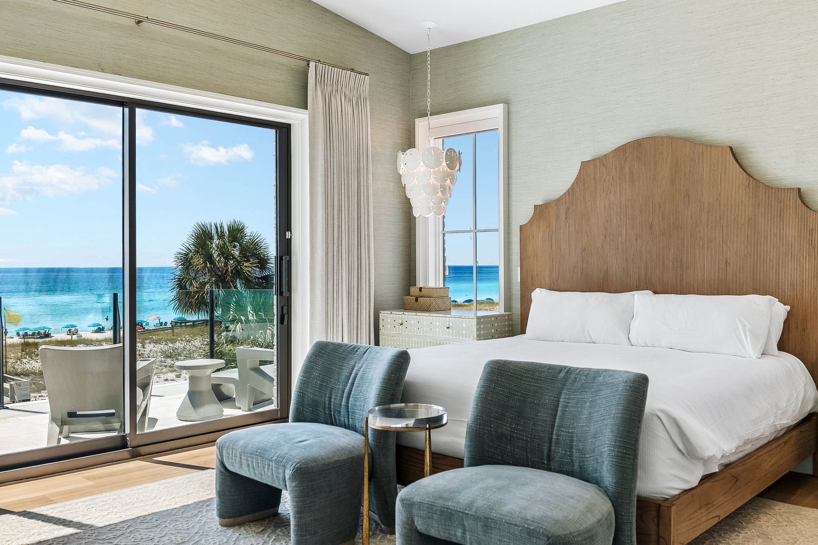 Wake up to the sound of waves from your dreamy coastal bedroom, where floor-to-ceiling windows frame sweeping ocean views and natural textures create a soothing retreat.