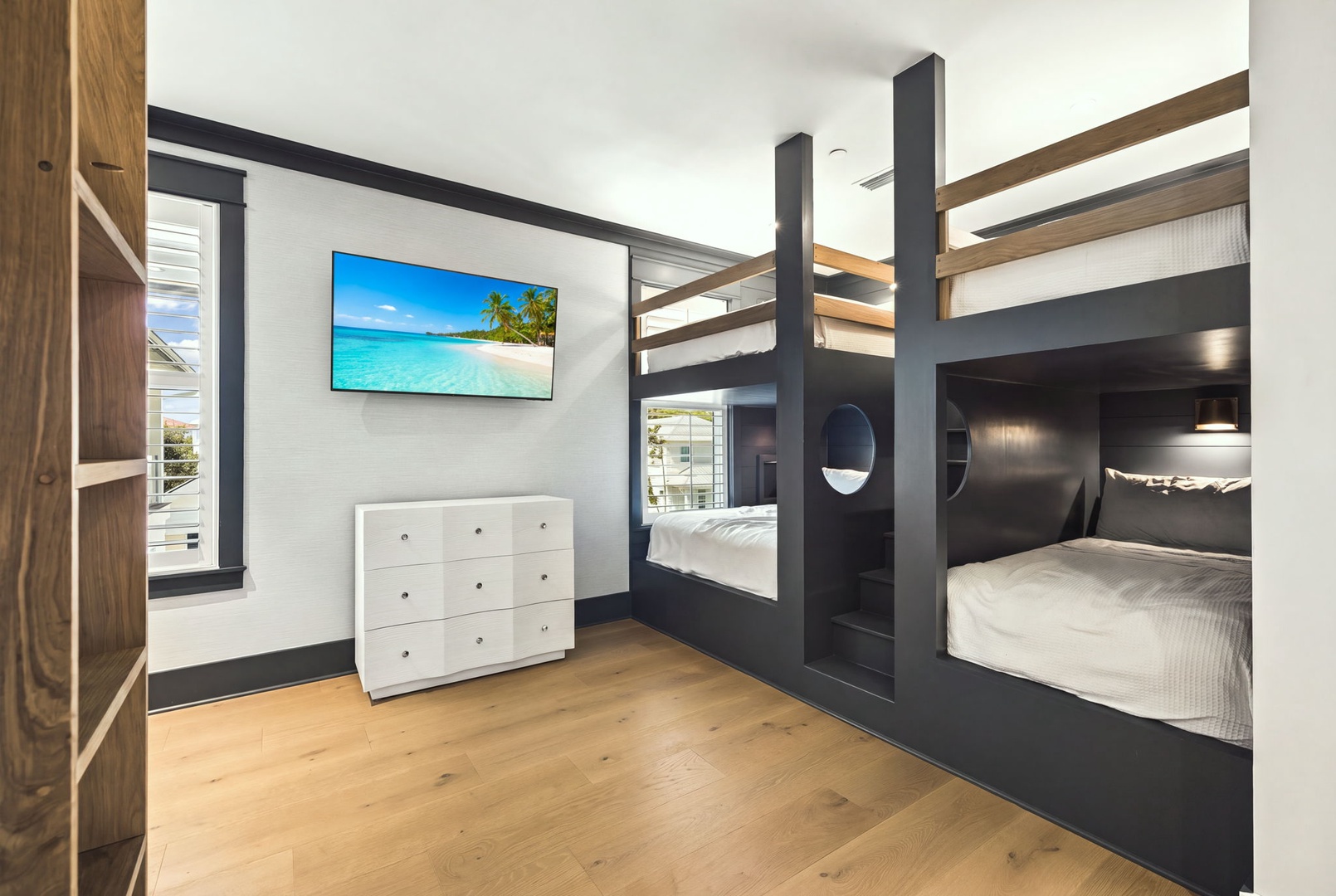 Your stylish bunk room features modern built-in beds with storage, sleek black frames, and warm wood accents—perfect for kids or groups who want comfort and fun together.