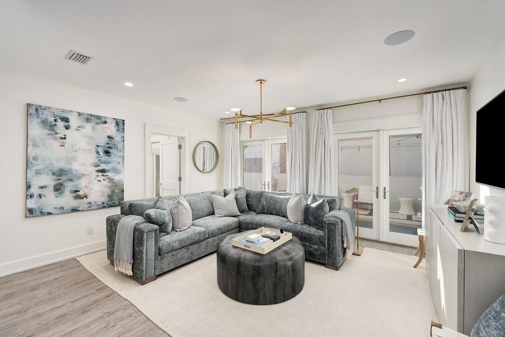 Sink into plush seating in your elegant living room, where contemporary art and designer lighting create an inviting atmosphere. French doors open to additional spaces, perfect for unwinding after a day of exploring.