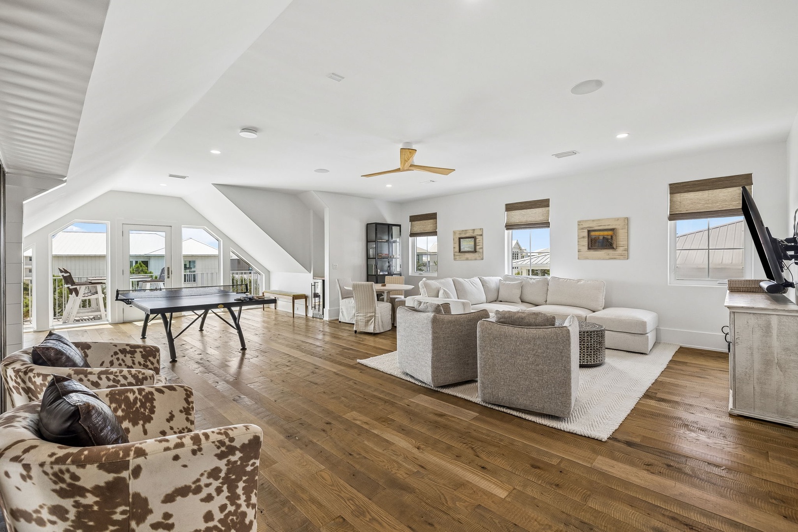 Step into your open-concept living space where high ceilings and abundant natural light create an airy, welcoming atmosphere. Relax on plush seating, enjoy games at the table, and soak in peaceful ocean views through expansive windows.
