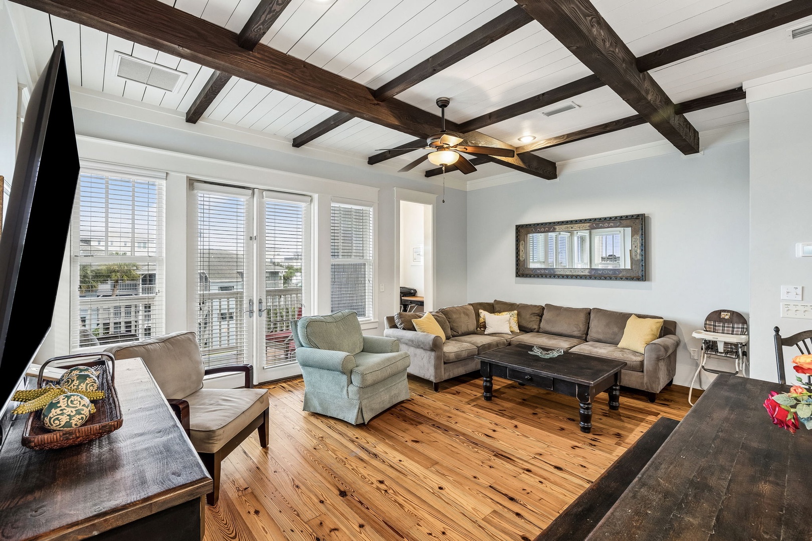 Step into your bright, open living space with soaring ceilings and rustic wood beams that add warmth and character. Relax on plush seating while natural light pours through expansive windows, and enjoy cozy evenings on gleaming hardwood floors.