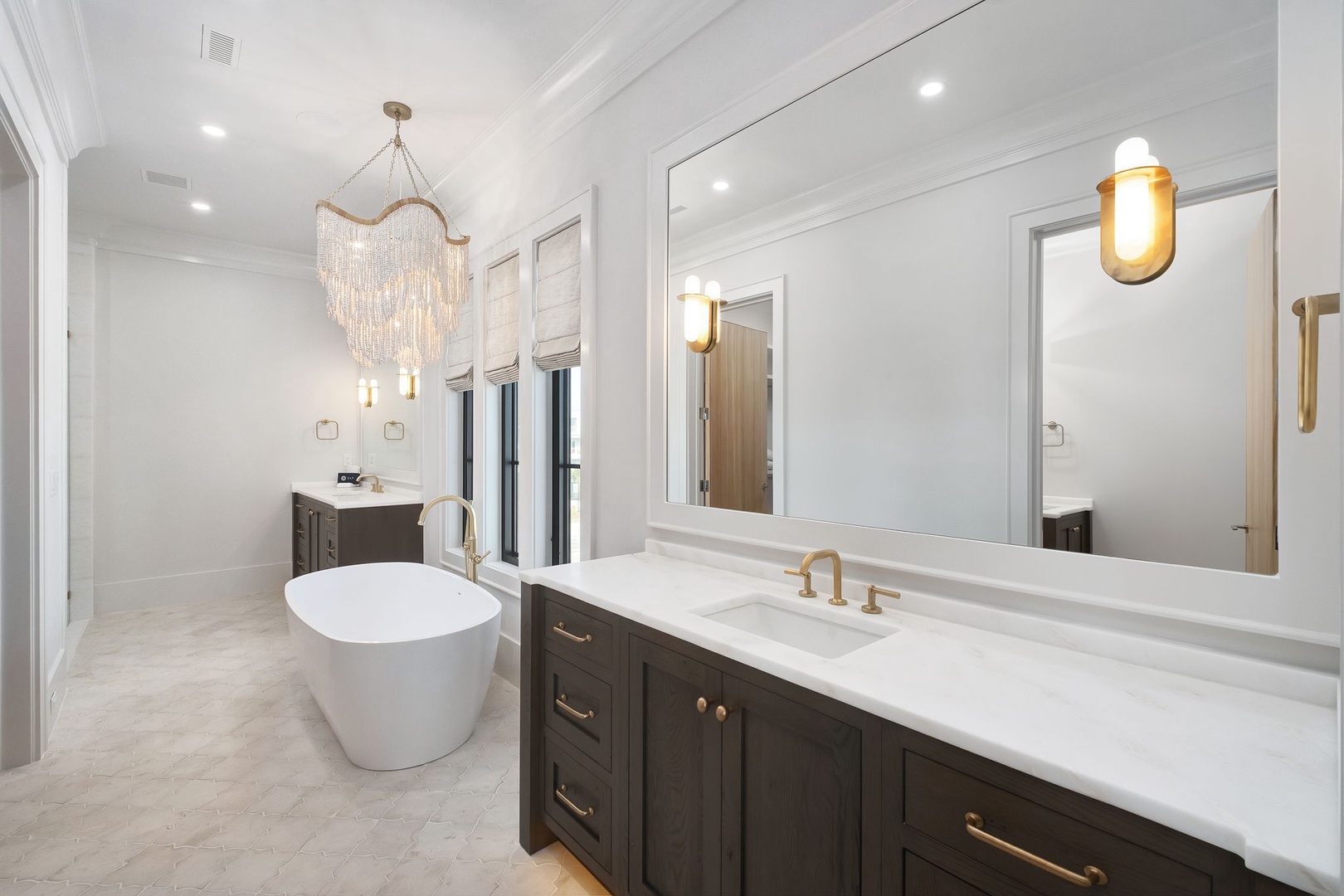Unwind in your luxurious spa-like bathroom featuring a stunning chandelier, elegant soaking tub, and sophisticated marble finishes.