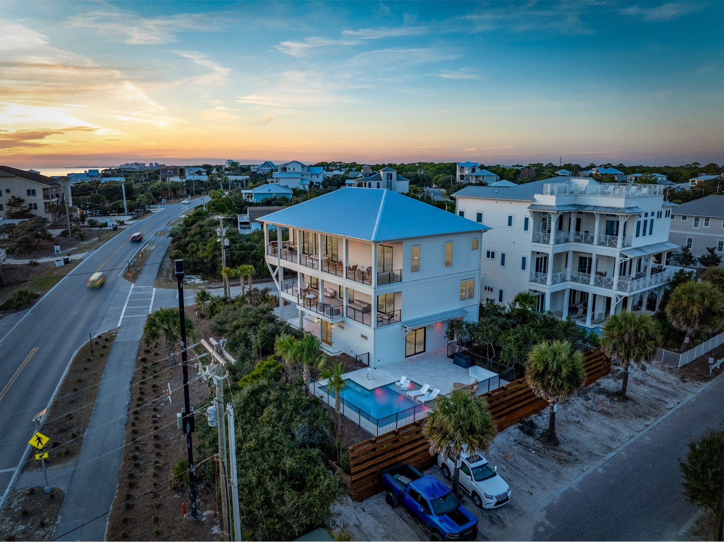 Stunning three-story coastal home with private pool nestled in a charming beachside neighborhood at golden hour.
