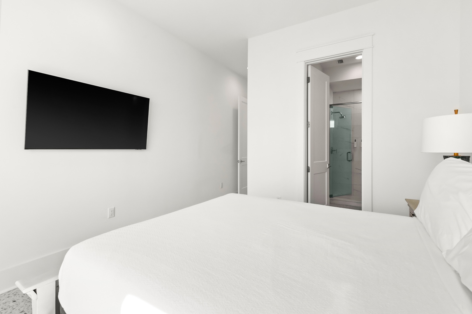 Sink into crisp white linens in your bright, minimalist bedroom. A private ensuite awaits just steps away, while your wall-mounted TV offers easy entertainment.