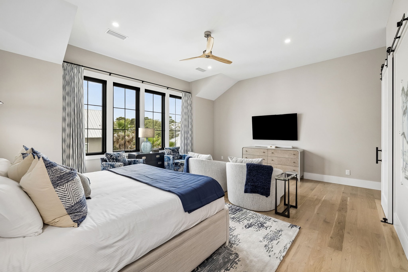 Sink into soft linens and watch the palms sway through your window—your peaceful retreat awaits with a cozy seating area, flat-screen TV, and ceiling fan overhead.