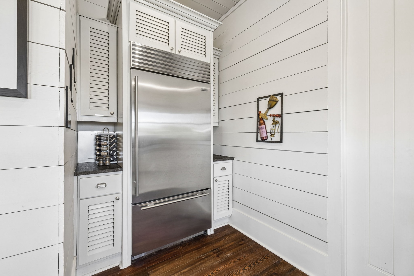 Gleaming stainless steel appliances meet crisp shiplap walls in your well-appointed kitchen, where modern convenience blends seamlessly with coastal cottage charm.
