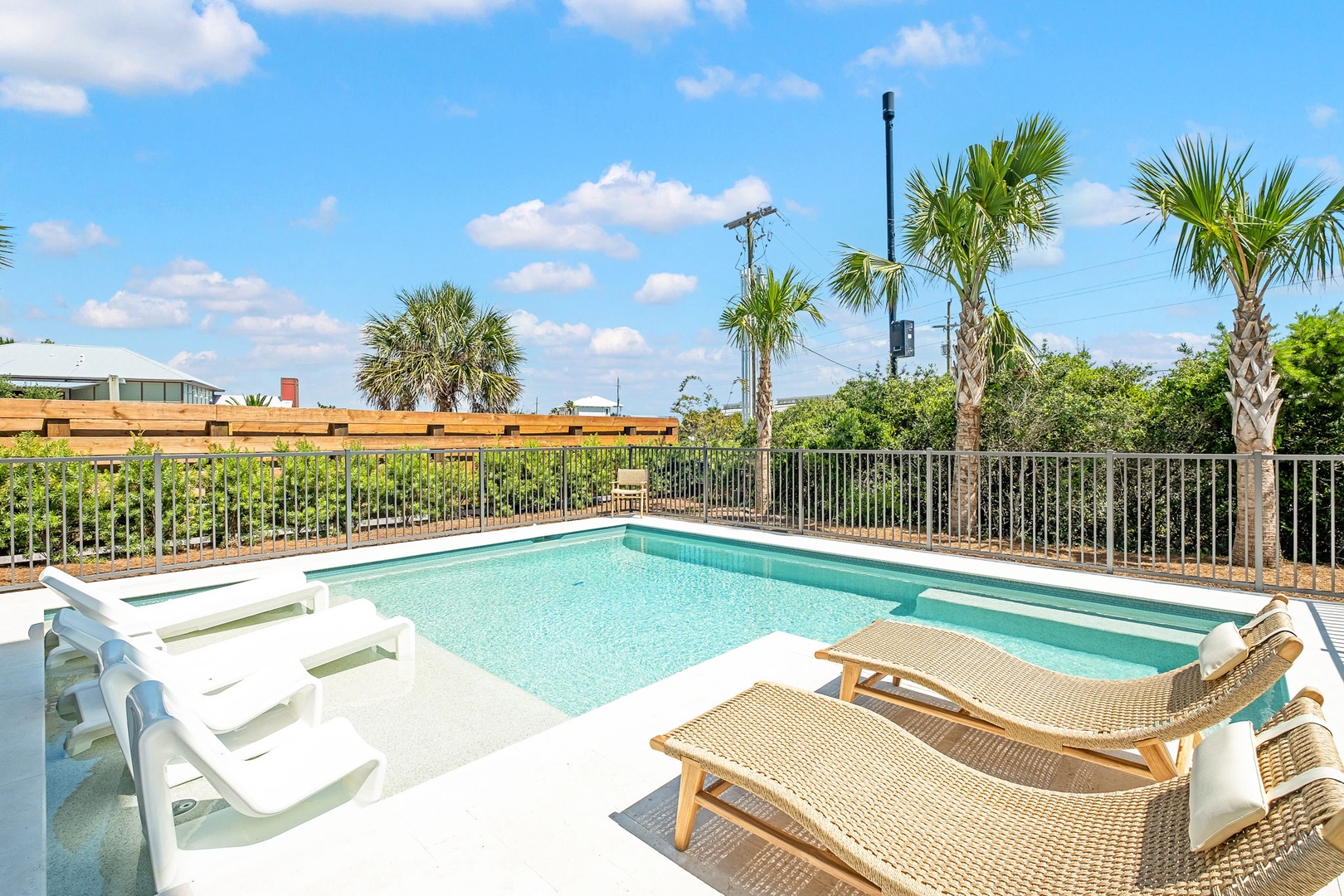 Sparkling private pool awaits with sun loungers and white chairs—picture your morning coffee or afternoon cocktails surrounded by palm trees and sunny skies.