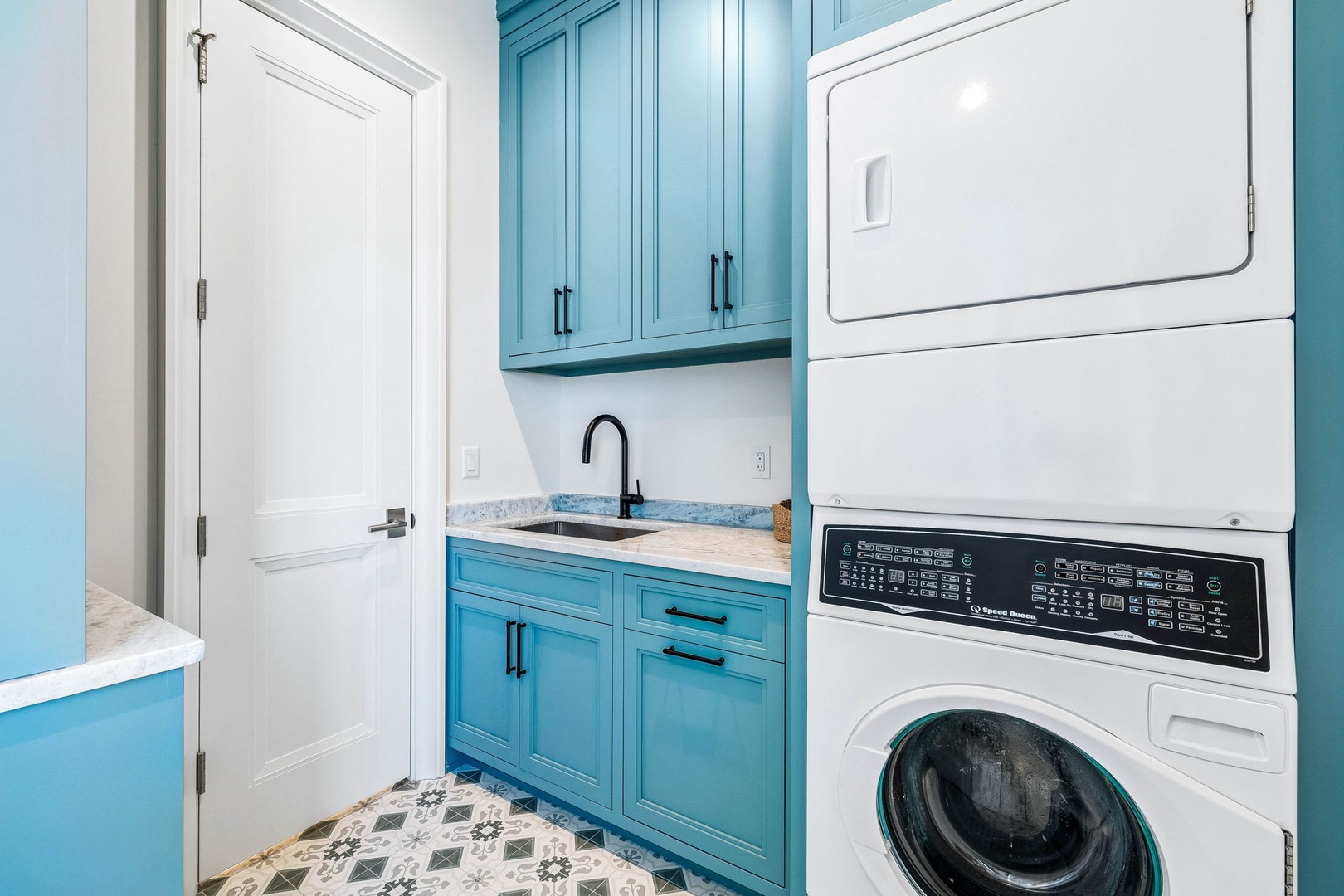 Step into your stylish laundry room with vibrant turquoise cabinetry and a modern stacked washer-dryer combo—chores have never looked this inviting!