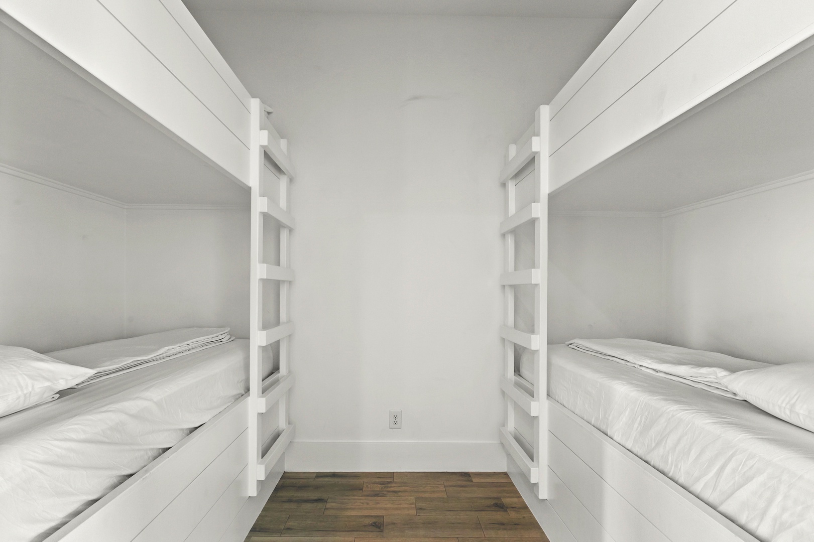 Cozy bunk room with crisp white linens and built-in ladder access, perfect for your group or family to rest comfortably after a day of adventures.