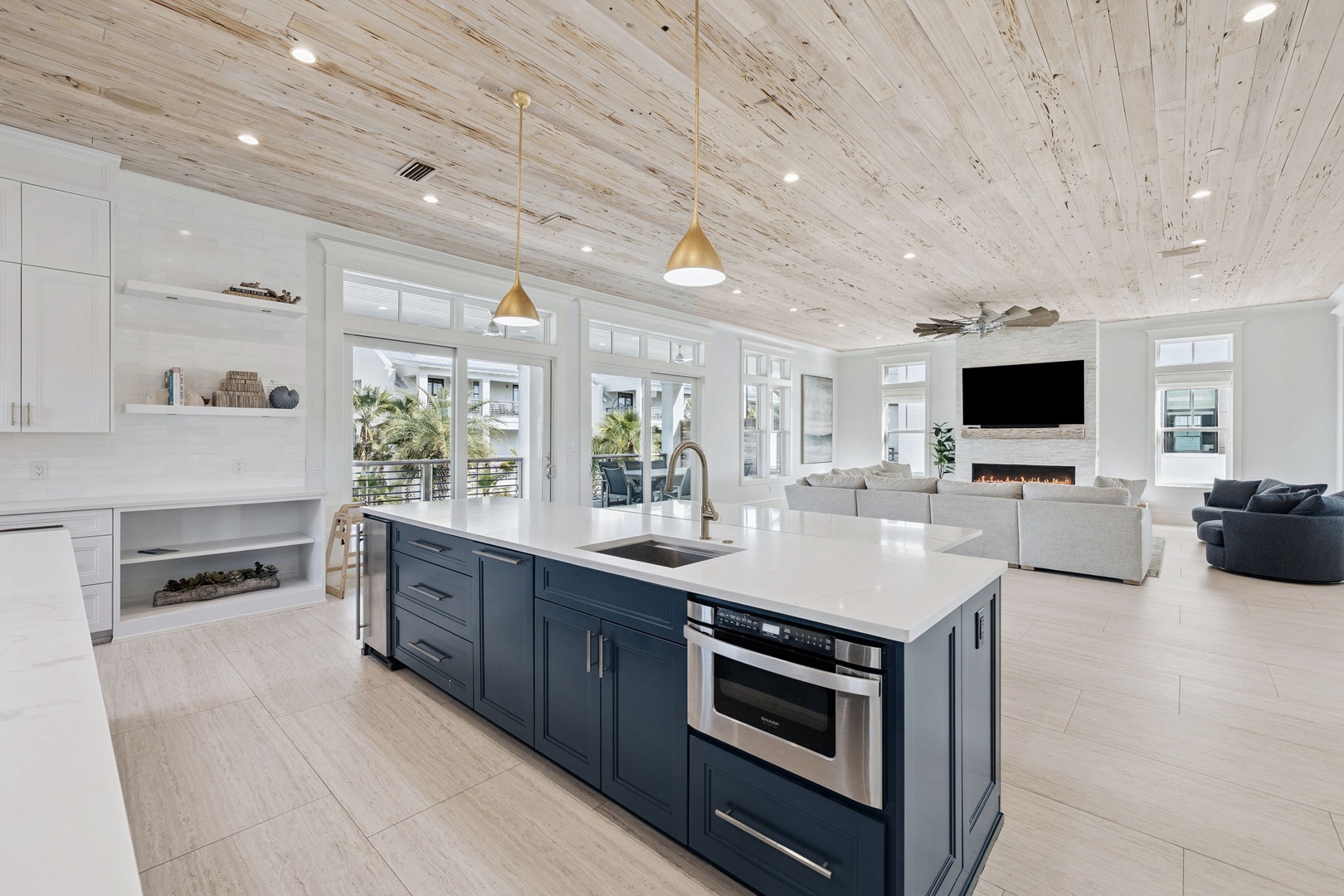 Unwind in your stunning open-concept space featuring soaring whitewashed wood ceilings, a chef's dream kitchen island, and cozy living area with fireplace.
