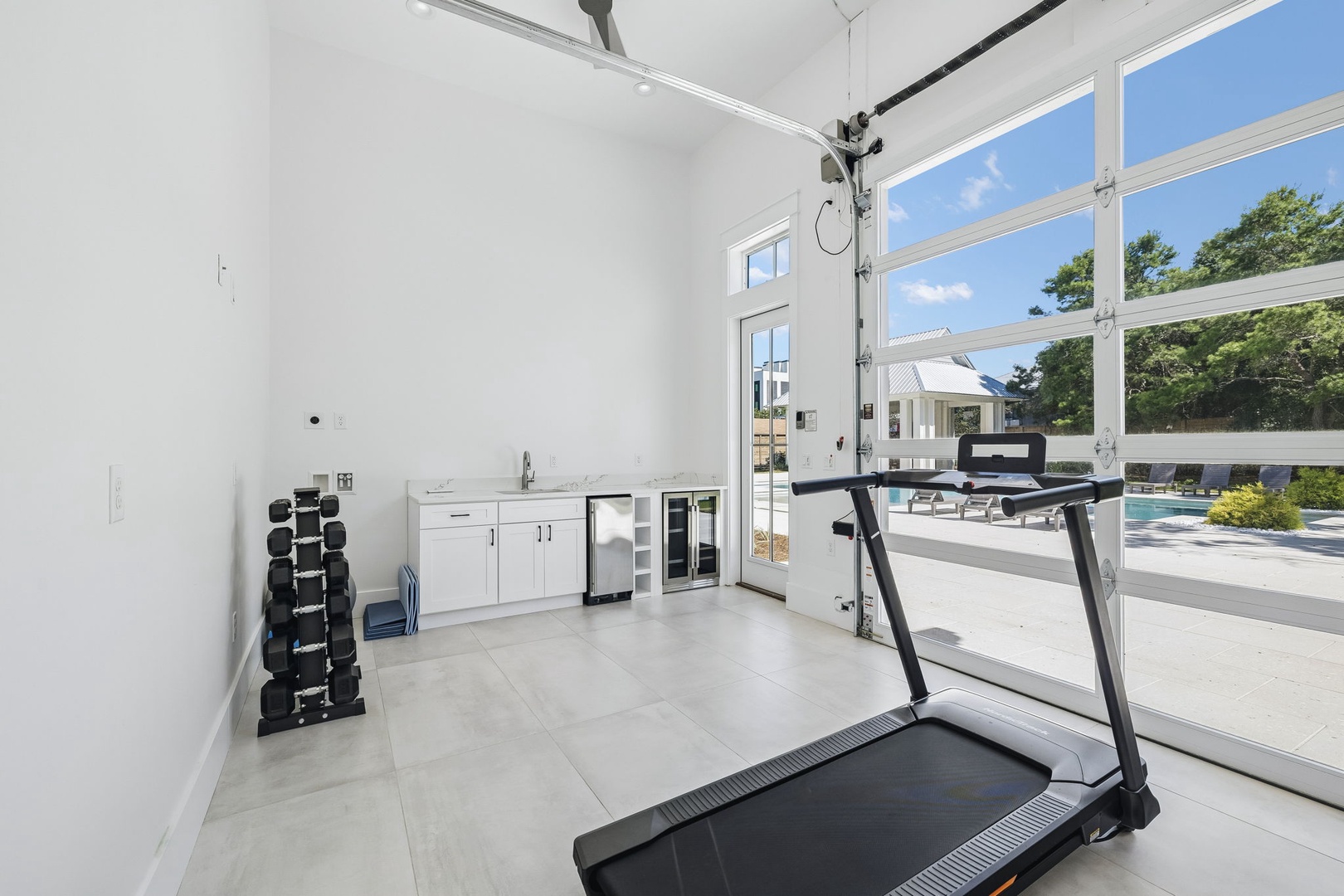Your private fitness space awaits with modern equipment and floor-to-ceiling windows overlooking the pool, where natural light energizes every workout.