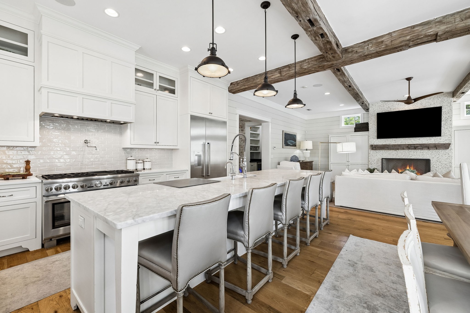 Stunning kitchen with rustic exposed beams, marble countertops, and a grand island. The cozy fireplace and open layout create a warm, welcoming heart of the home.