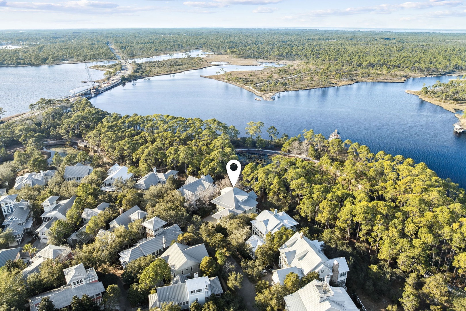 Aerial view showcases the property's prime lakefront location within a peaceful residential community surrounded by lush forests and waterfront access.