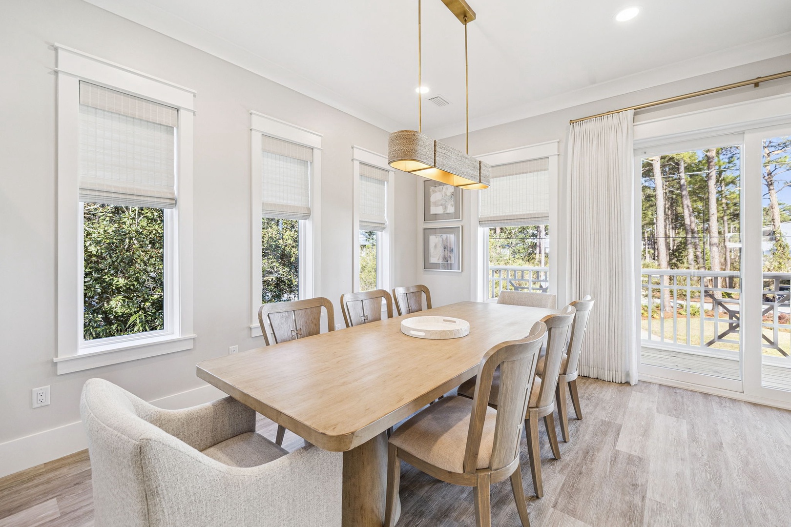 Gather around this beautiful dining table where sunlight streams through windows overlooking peaceful trees, perfect for sharing memorable meals together.