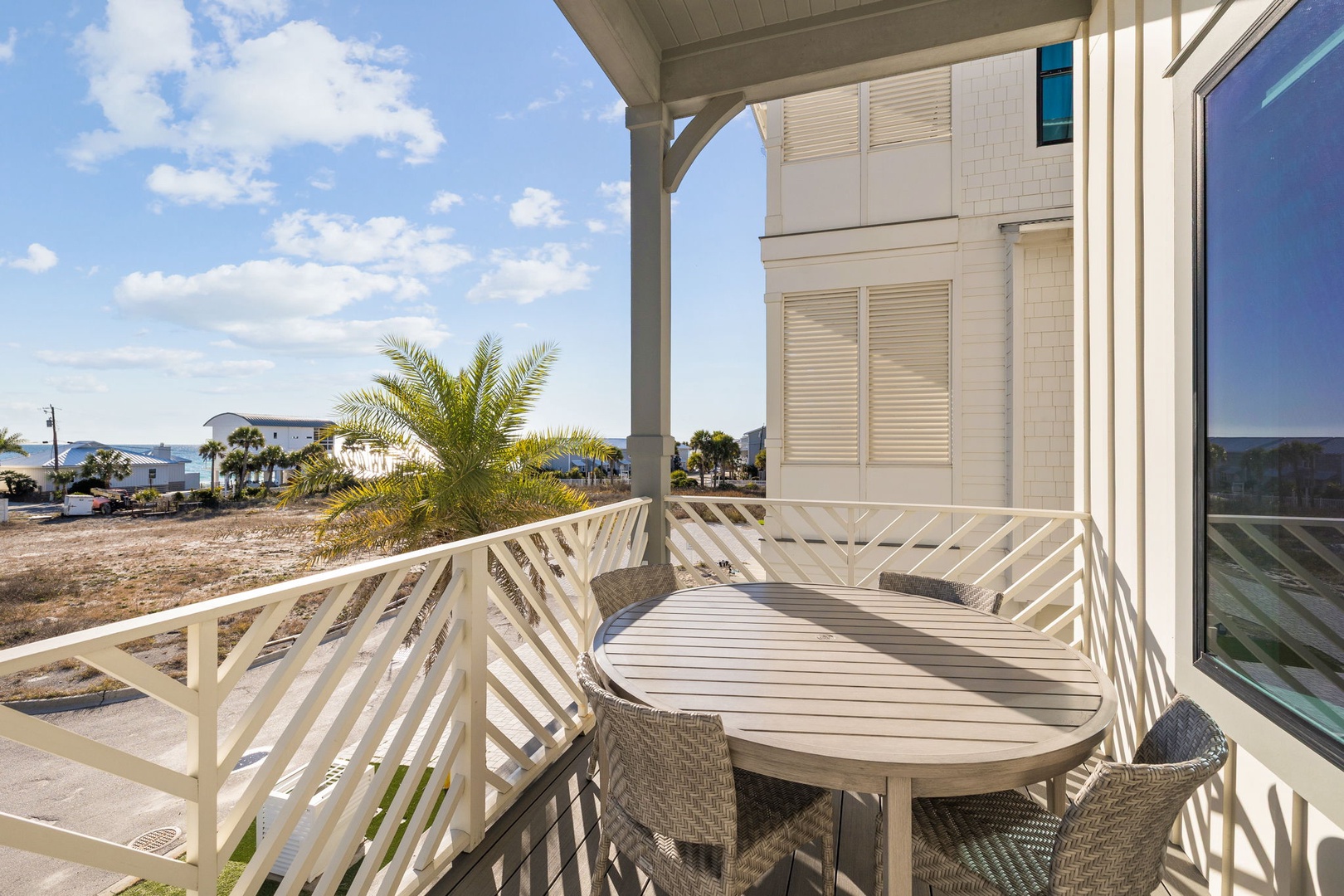 Spacious covered balcony with dining table where you'll enjoy meals with palm tree views and coastal scenery.