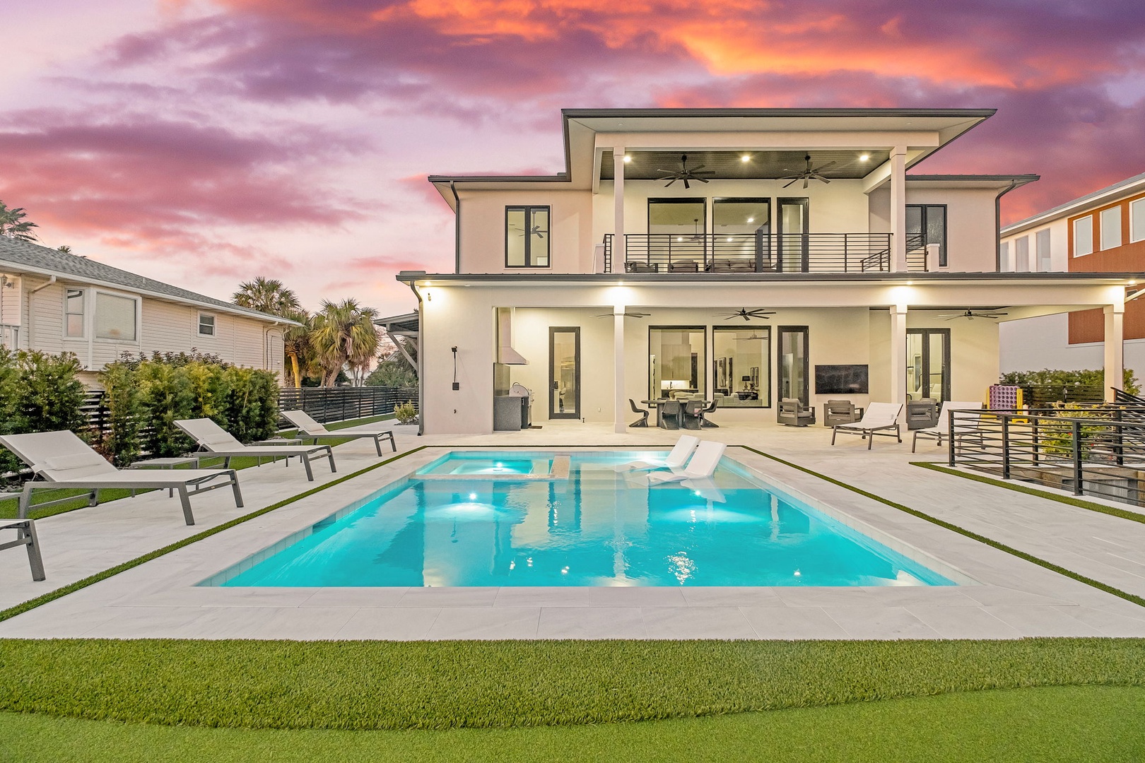 Modern luxury home showcases stunning contemporary architecture with pristine pool, surrounded by tropical palms under vibrant sunset skies.