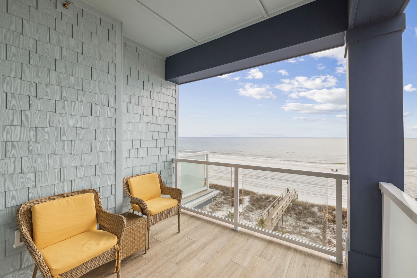 Relax in comfortable wicker chairs while soaking up panoramic beach views from your private covered balcony.