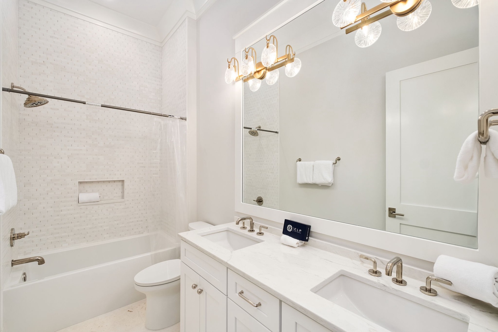 Pamper yourself in this elegant bathroom featuring marble countertops, dual vanities, and gleaming gold fixtures that create a luxurious spa-like retreat.