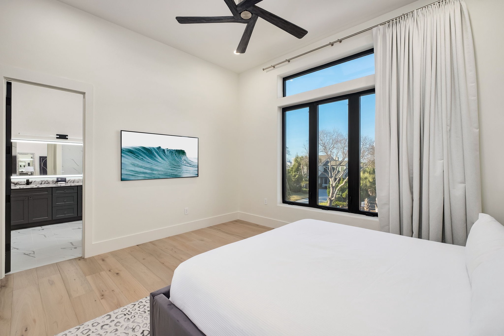 Rest in your bright, peaceful bedroom with soft linens and gentle breezes from the ceiling fan above.