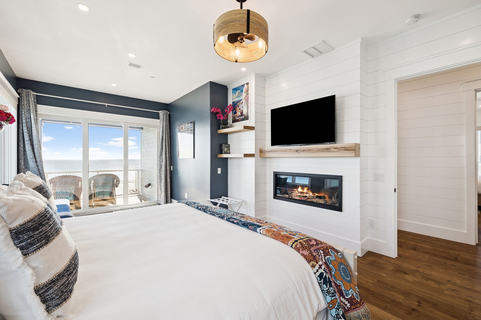 Unwind in your elegant bedroom featuring a cozy fireplace, modern TV setup, and stunning ocean views from your private balcony.