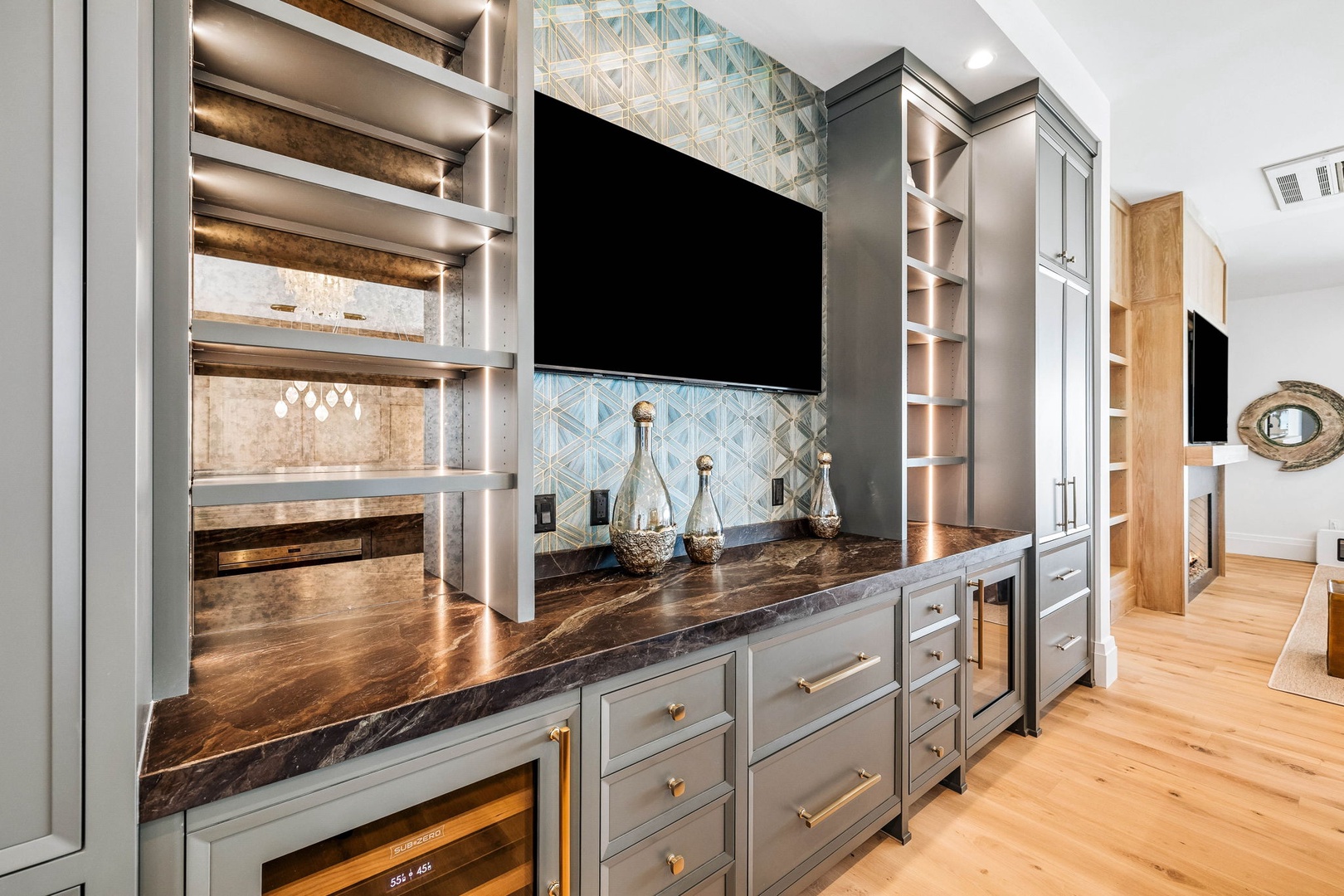 Your entertainment hub awaits with custom cabinetry, a sleek media wall, and a beverage fridge—perfect for movie nights or lazy mornings with coffee in hand.