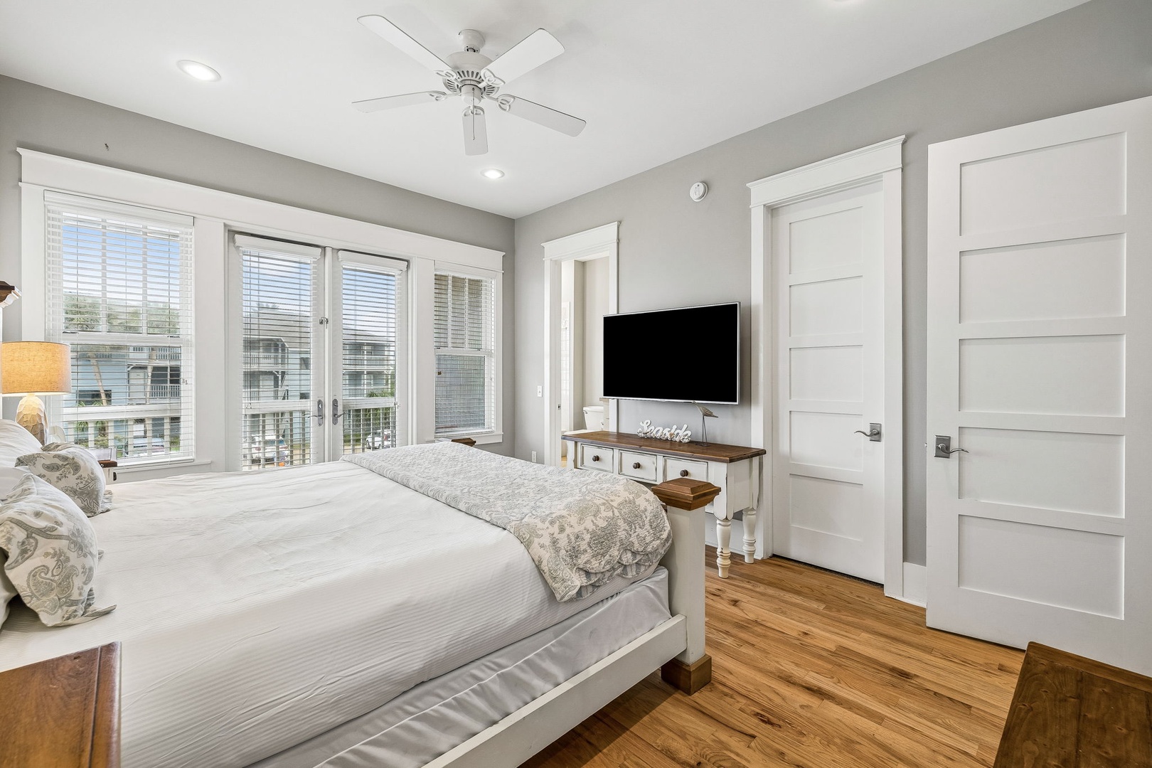 You'll love waking up in this peaceful bedroom where sunlight streams through the windows and a ceiling fan keeps you comfortable. Warm hardwood floors and farmhouse-style touches create a restful retreat.