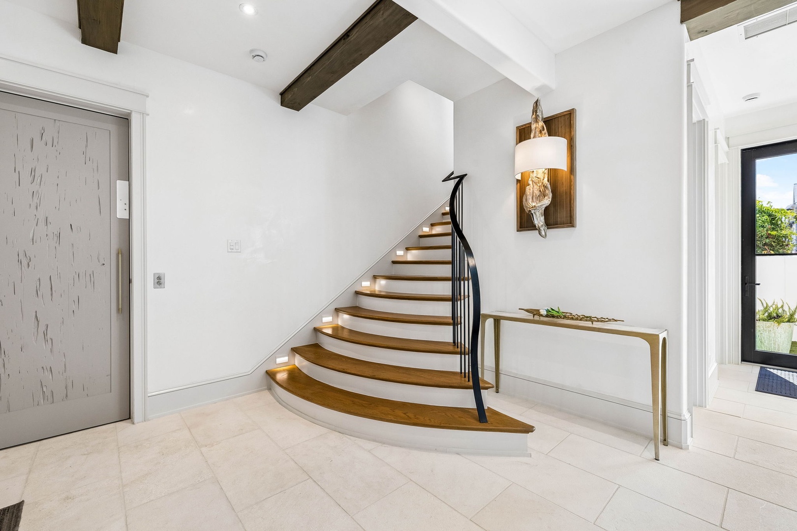 Step through the front door into a bright, inviting entryway where rustic wood beams meet elegant curves. The spiral staircase beckons you upward, while natural light floods the space, setting a warm, welcoming tone for your stay.