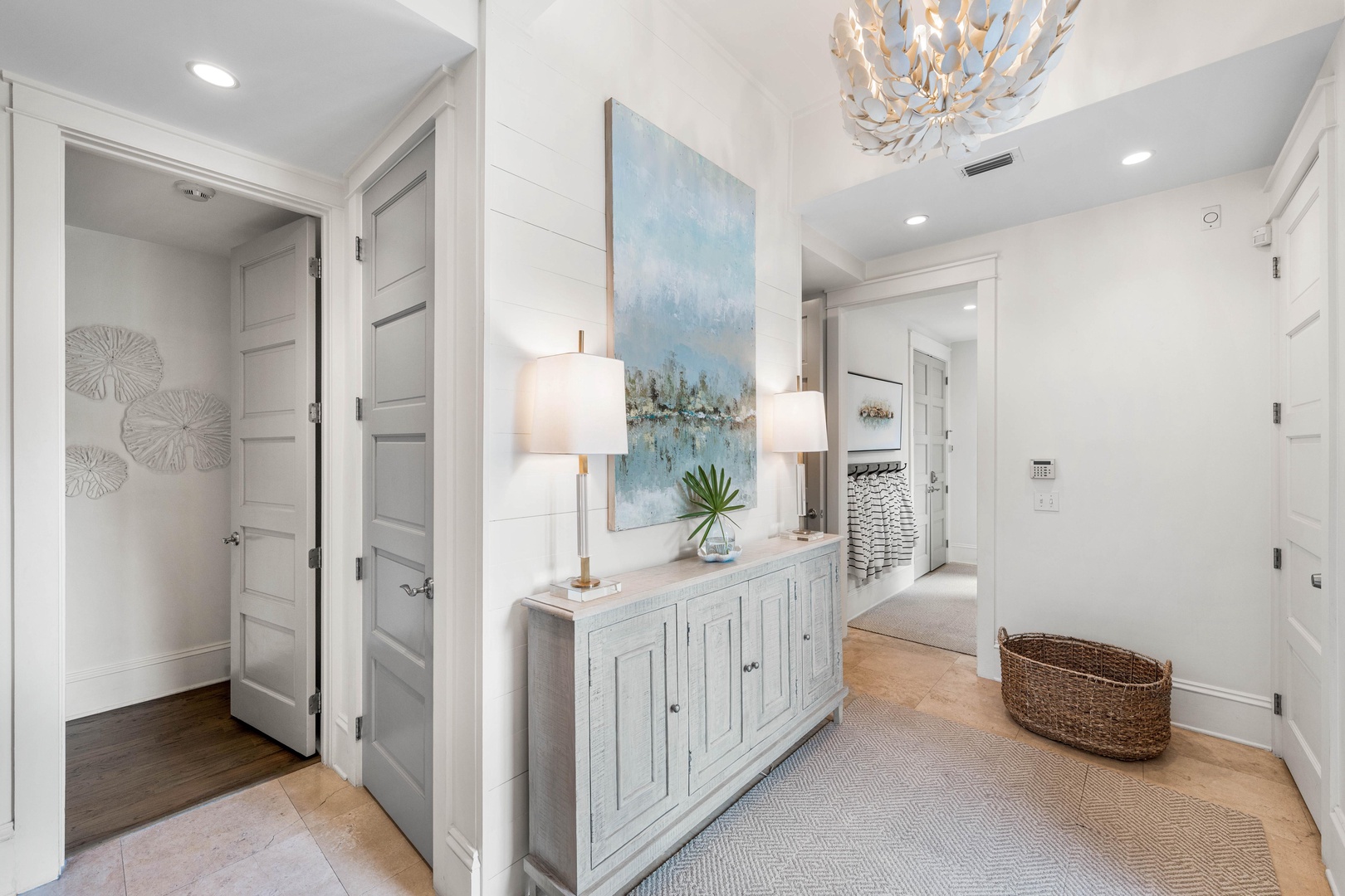 Step into your elegant hallway where coastal artwork and warm lighting create a welcoming first impression of your refined retreat.