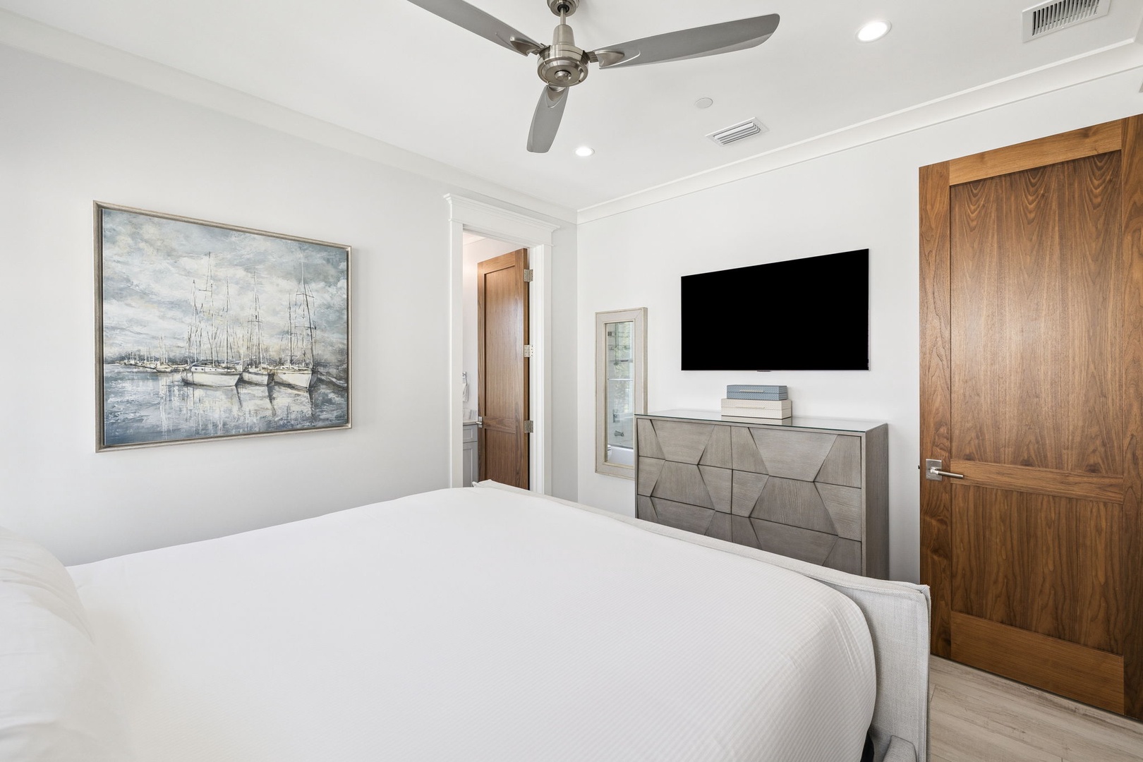 Drift off in your serene bedroom with crisp white linens, stylish art, and modern amenities for ultimate comfort.