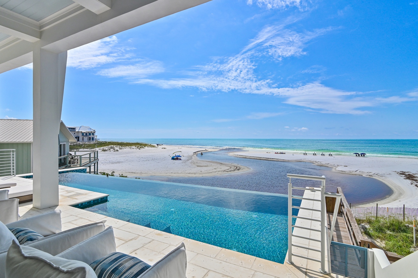 The property features a private infinity pool overlooking pristine beachfront and emerald Gulf waters, with a coastal waterway winding through soft white sand dunes.