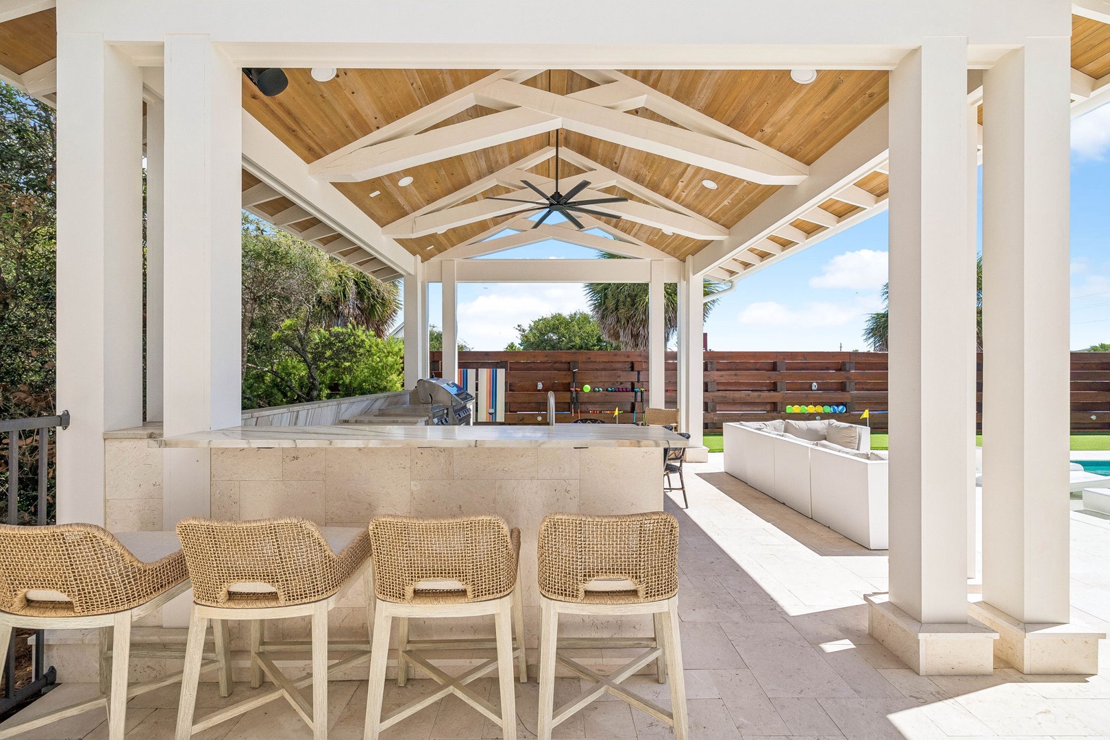 Gather around this stunning covered outdoor bar with its soaring wood-beamed ceiling and sleek stone counters—your own private oasis for poolside entertaining and al fresco dining.