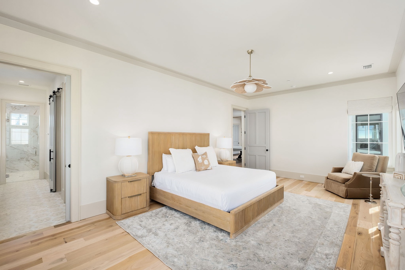 Sink into crisp white linens in your spacious master suite, where warm wood tones and soft lighting create the perfect sanctuary for rest.