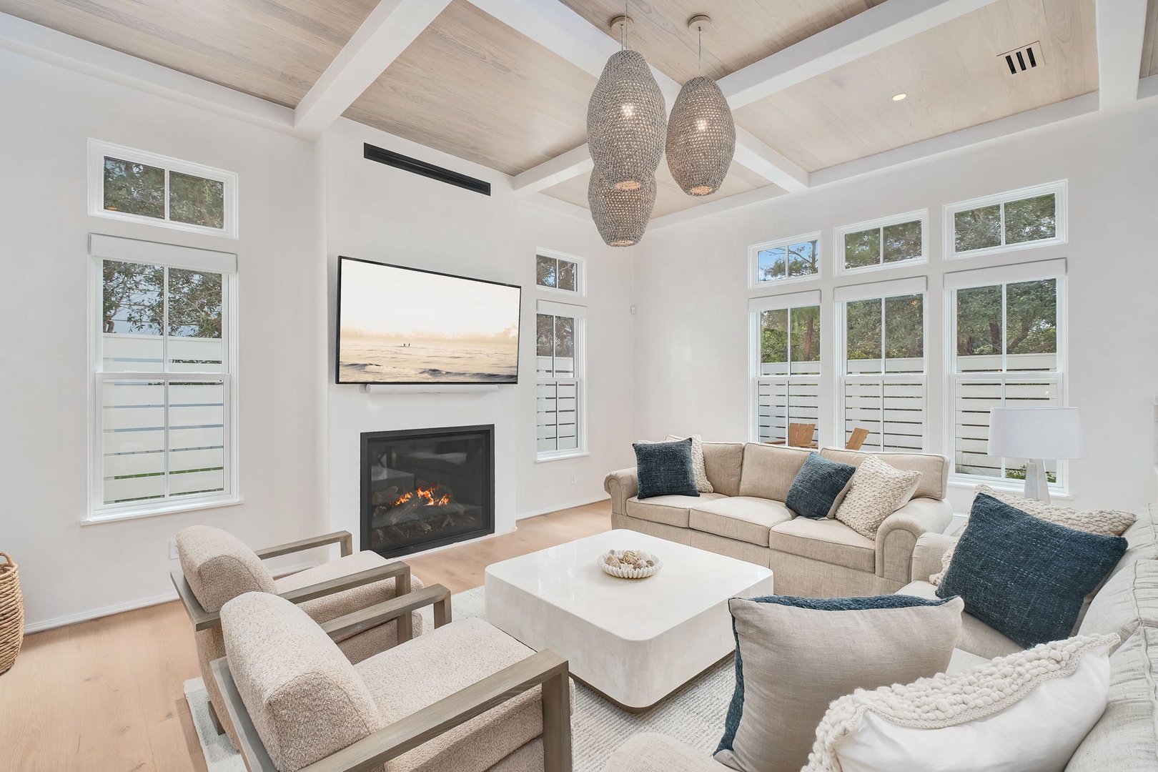Sink into plush seating by the glowing fireplace and let coastal calm wash over you—high ceilings and natural light make this your retreat within the retreat.