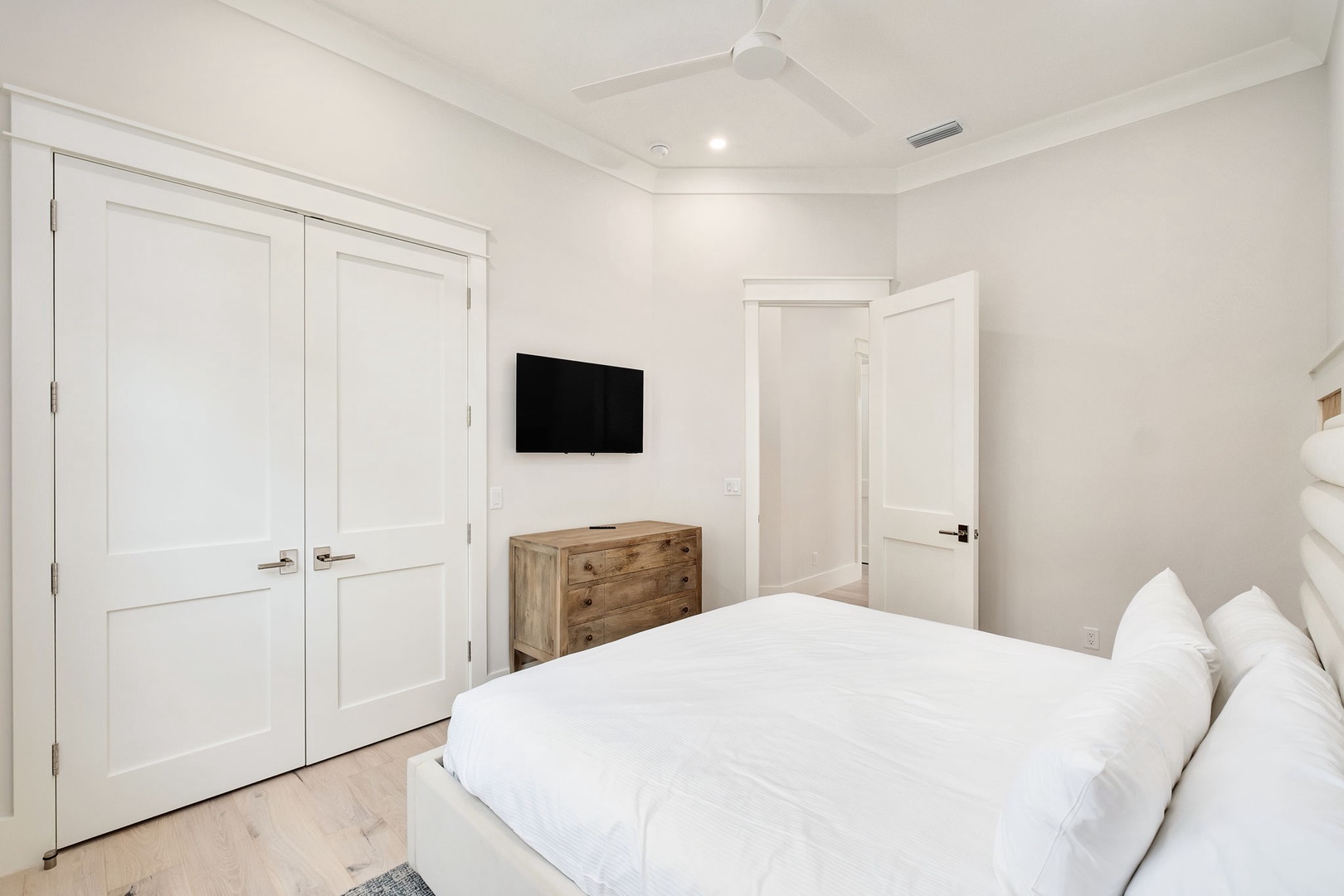 Slip into crisp white linens in your serene bedroom, where a ceiling fan keeps you cool and rustic-modern touches create the perfect retreat.