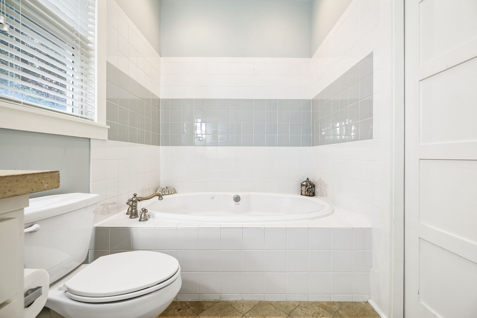 Sink into the deep soaking tub after a long day—this spa-like bathroom offers a peaceful retreat with elegant tile work and plenty of natural light from the window.
