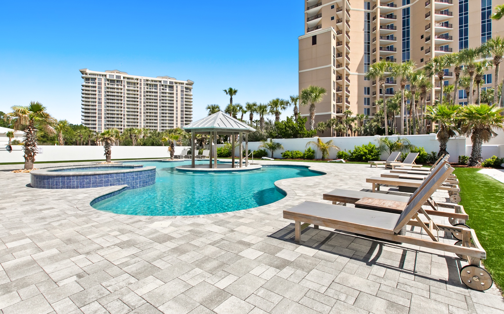 The resort-style pool area features a tropical oasis with palm trees, lounge chairs, and a swim-up gazebo. Relax poolside on comfortable sunbeds surrounded by lush landscaping under sunny blue skies.