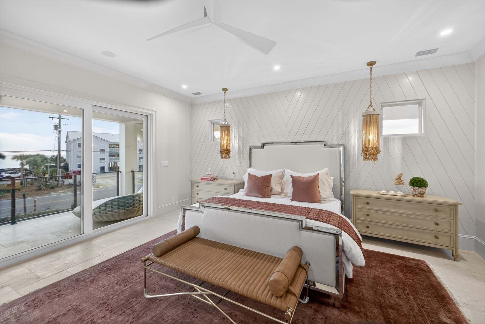Your spacious bedroom features elegant pendant lighting, cozy bedding, and large windows offering views of the coastal neighborhood.