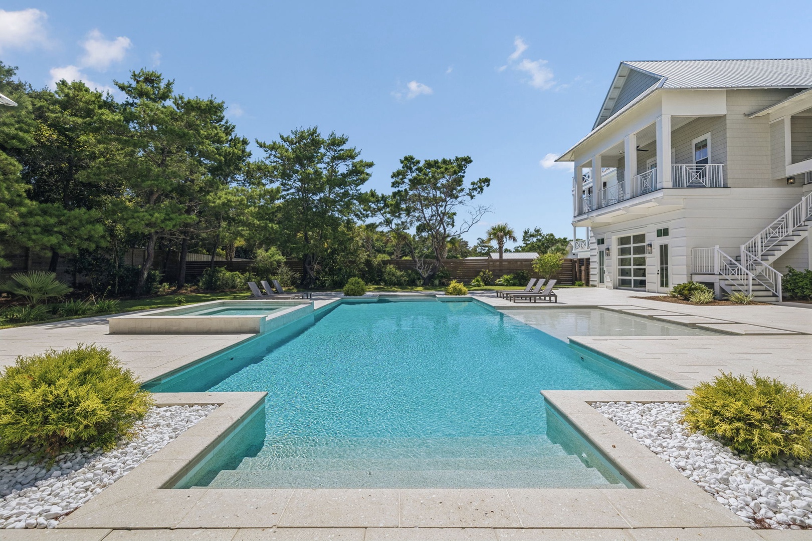 This coastal retreat features an expansive custom pool surrounded by manicured landscaping and elegant architecture, offering a serene private oasis for relaxation and entertaining.