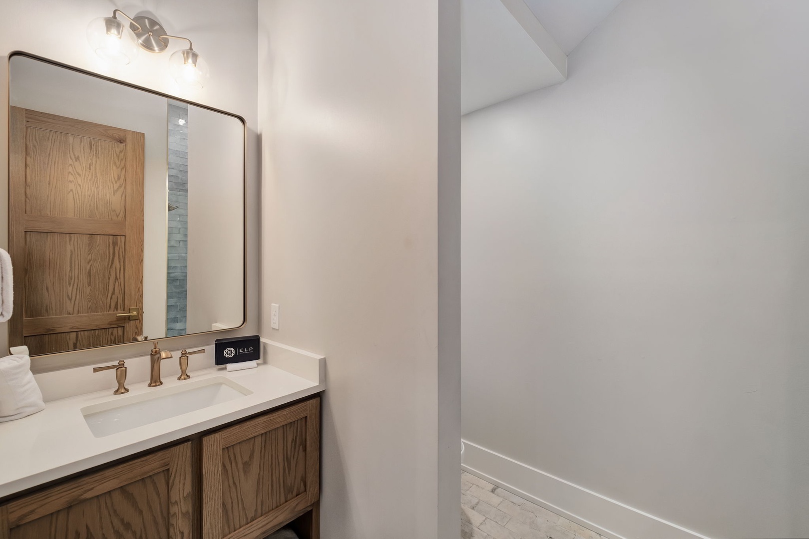 Step into your private spa-like bathroom with warm wood vanity, elegant lighting, and pristine white surfaces for ultimate relaxation.