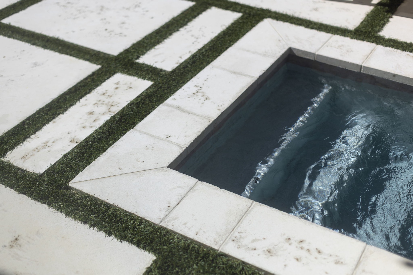 A sleek plunge pool set into modern stone pavers with lush grass borders—your private oasis for cooling off on warm days.